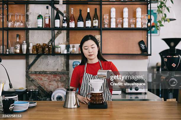 barista preparing a pour-over coffee in a trendy cafe setting - cafe culture stock pictures, royalty-free photos & images