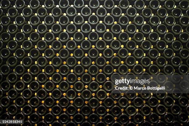close-up of countless wine bottles stacked in a dim cellar - cave à vin photos et images de collection