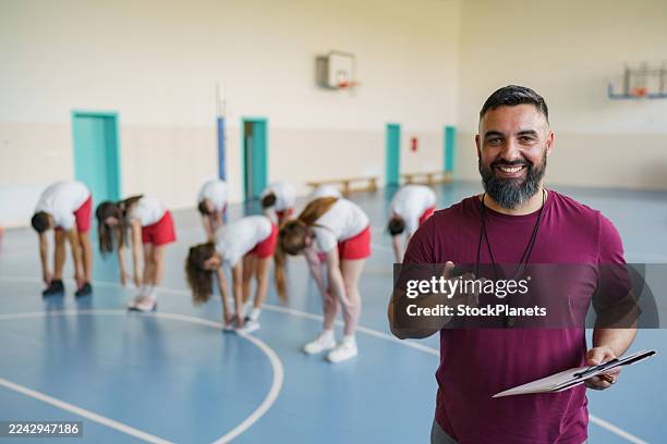 coach smiling during p.e. class with students stretching - educational subject stock pictures, royalty-free photos & images