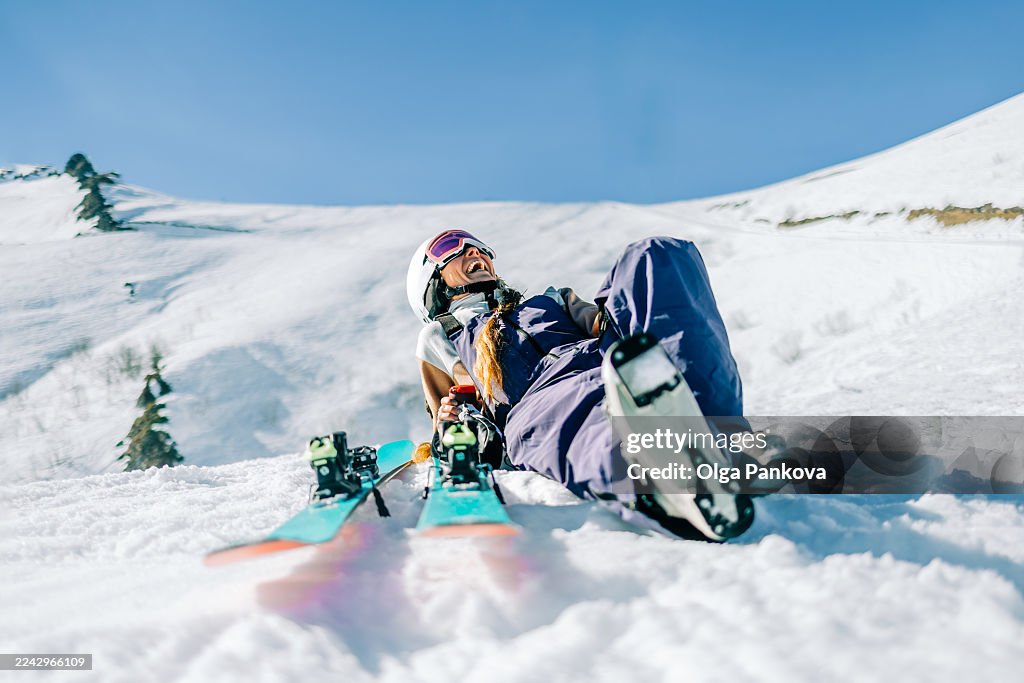 Happy woman skier laughing and relaxing on snowy mountain with ski