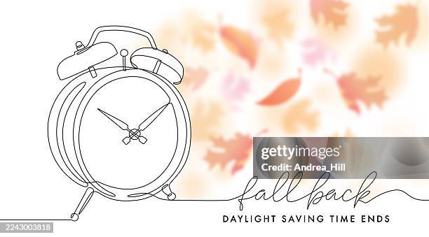 fall back daylight saving time message with alarm clock and bokeh falling leaves. copy space for text. - fall back stock illustrations