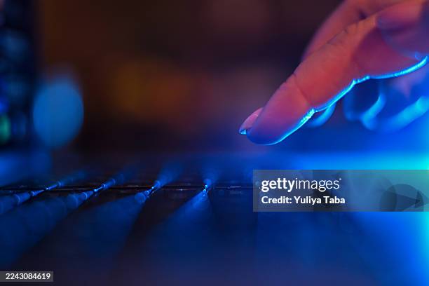 dito umano che tocca la tastiera del computer portatile con la luce blu - tastiera di computer foto e immagini stock