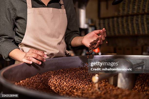 roaster hands handling coffee beans in large metal drum for fresh aromas and small-batch craftsmanship - artisanal food and drink stock pictures, royalty-free photos & images