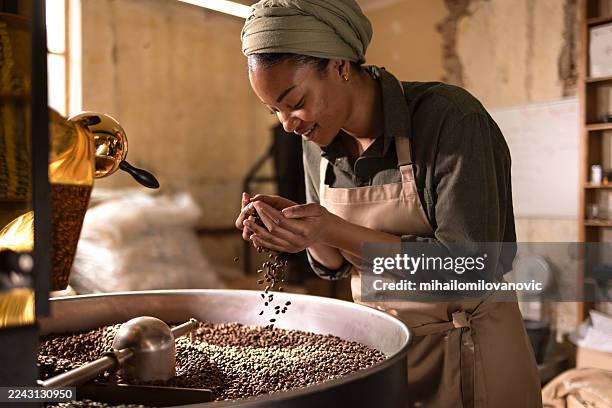 female barista roasting coffee beans in a warm studio cafã© setting - artisan stock pictures, royalty-free photos & images