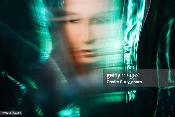 an abstract portrait of a woman with motion blur and turquoise streaks of light. the image conveys an atmosphere of mystery, introspection, and the fusion of human emotion with digital abstraction. - deepfake stock pictures, royalty-free photos & images