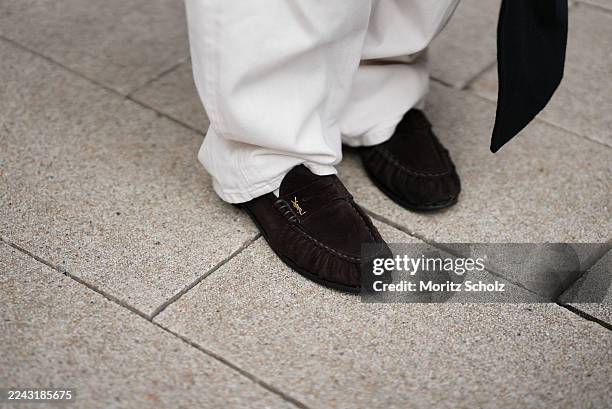 Isabelle Hartmann is seen wearing white denim trousers in a loose fit by Aylin König; brown suede leather loafers with a low stacked heel and ruffled...