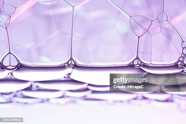purple soap bubbles floating on water close-up view - durchsichtig stock-fotos und bilder