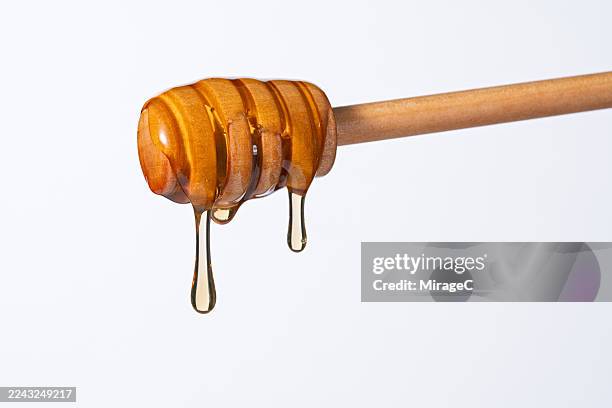 honey dripping from wooden honey stick - honing stockfoto's en -beelden