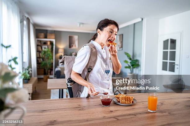 nurse in uniform eating quick breakfast before work - quick meal stock pictures, royalty-free photos & images