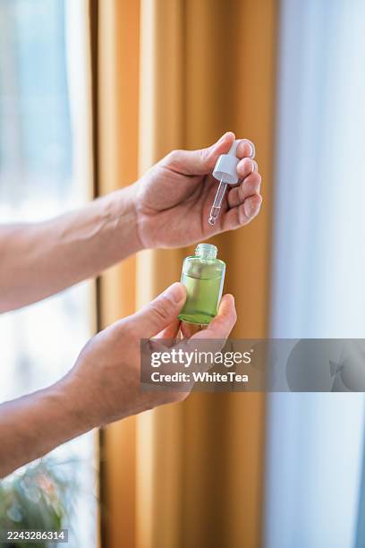 hands with dropper bottle of green serum for skincare routine - facial oil stock pictures, royalty-free photos & images