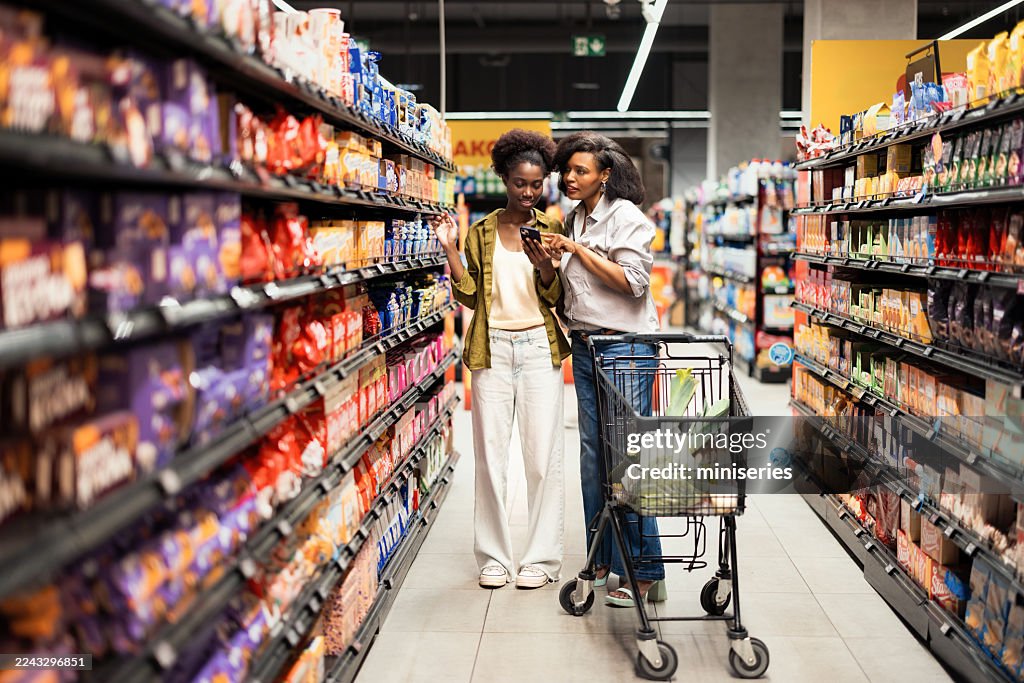 Mother And Daughter Shopping Together In A Bright Grocery Store Aisle