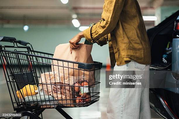 mère et fille faisant leurs courses ensemble dans un parking avec chariot d’épicerie et voiture - équipement domestique photos et images de collection