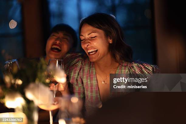 joyful dinner party with friends laughing and toasting glasses at cozy evening - crystal glassware stock pictures, royalty-free photos & images