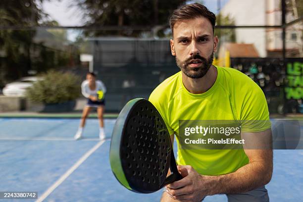 focused male padel player preparing to strike ball - paddle ball stock pictures, royalty-free photos & images
