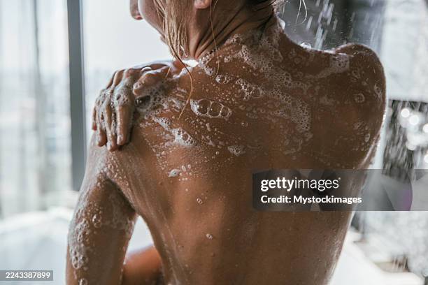 woman washing shoulder under shower spray - shower gel stock pictures, royalty-free photos & images