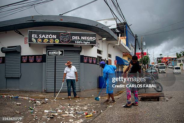 People clean a street after the passing of the tropical storm Melissa before becoming a hurricane in Barahona, Dominican Republic on October 28, 2025.