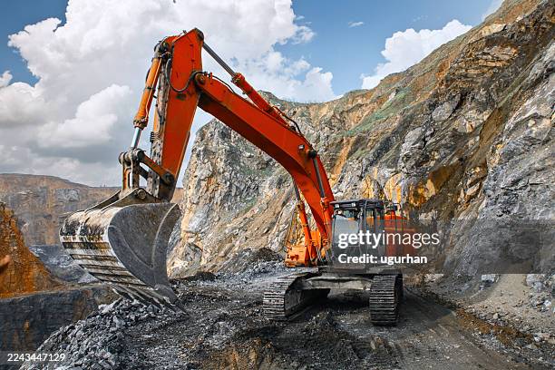 excavadora naranja trabajando en cantera de piedra - mina abierta fotografías e imágenes de stock