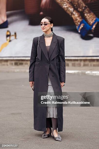 Guest wears a long dark grey pinstripe coat layered over a metallic tiered skirt and sheer leggings, styled with grey bow flats, a crystal statement...
