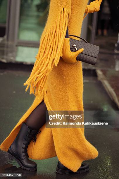 Viktoria Abduly wears a mustard-yellow knit dress with side fringe details and matching gloves, styled with black lace-up combat boots and a...