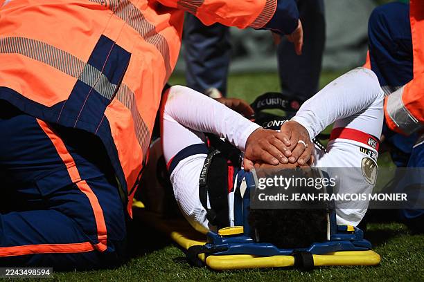 Paris Saint-Germain's French midfielder Desire Doue reacts in pain after suffering an injury during the French L1 football match between FC Lorient...