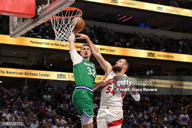 Cooper Flagg of the Dallas Mavericks dunks over Sandro Mamukelashvili of the Toronto Raptors during the second half at American Airlines Center on...