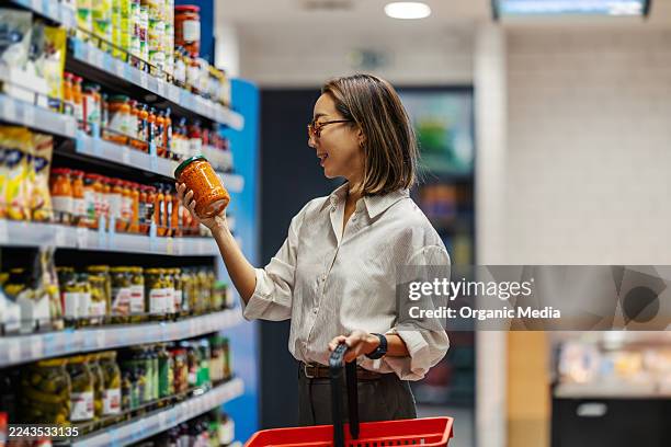 woman shopping for groceries in supermarket aisle - gemak stockfoto's en -beelden