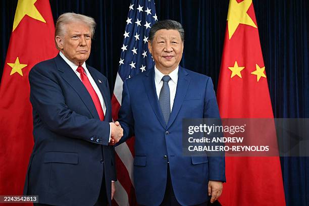 President Donald Trump and China's President Xi Jinping shake hands as they arrive for talks at the Gimhae Air Base, located next to the Gimhae...