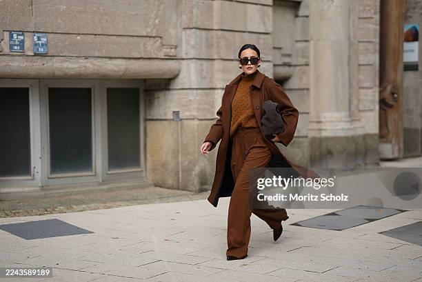 Laura Noltemeyer is seen wearing a long straight tailored wool coat in chocolate brown with button fastening by Sézane; high-waisted wide-leg pleated...