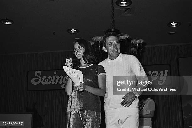 Franco-American singer and actress Claudine Longet, wearing a dark-coloured short-sleeve outfit with light-coloured trim, and her husband, American...