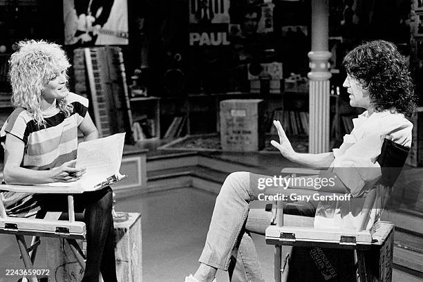 View of MTV VJ Nina Blackwood and American Rock musician Billy Squier, both sitting in director's chairs, during an interview at MTV Studios, New...