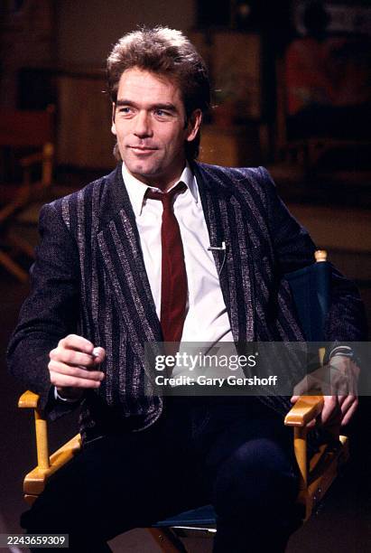 View of American Rock & Pop musician Huey Lewis as he sits in a director's chair during an interview at MTV Studios, New York, New York, January 3,...