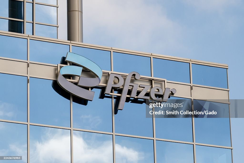 Pfizer Building Sign Pfizer logo on glass office building facade with sky reflections ...