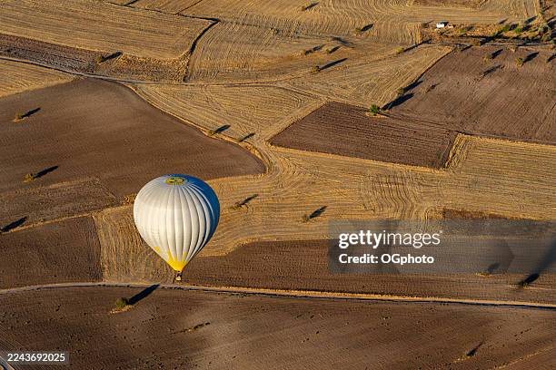 silver hot air balloon over farm fields in cappadocia, turkey - vanuit een heteluchtballon stockfoto's en -beelden