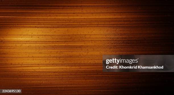 The golden brown texture background with horizontal lines resembling wood or polished metal gives a warm and shimmering feeling, conveying a luxurious and classic feel in background design.