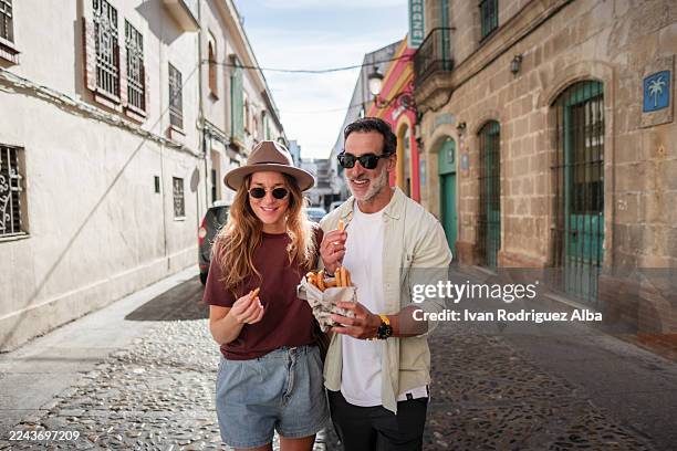 paar genießt churros auf einer alten europäischen straße - jerez de la frontera stock-fotos und bilder