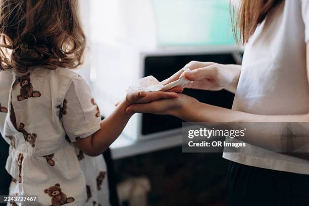 mother wiping hand of daughter at home - rubbing stock pictures, royalty-free photos & images