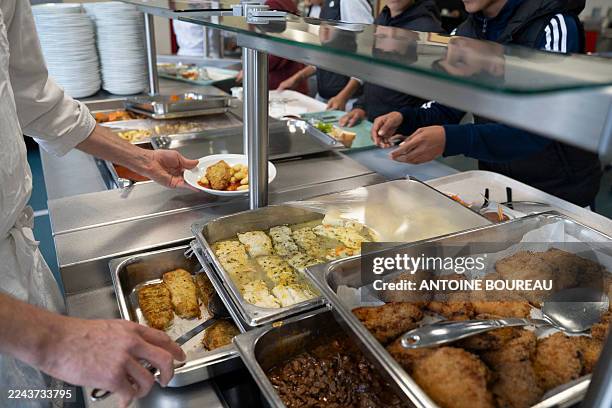 Secondary school pupil, a teenager helping himself to food in the school restaurant or canteen at Les Battieres secondary school in the 5th...