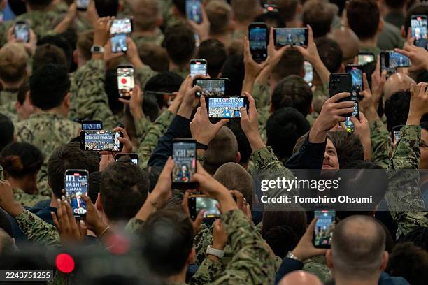 Soldiers use smartphones to record video of a speech by U.S. President Donald Trump aboard USS George Washington on October 28, 2025 in Yokosuka,...