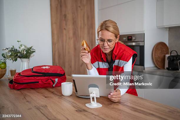 paramedic eating a snack and using a digital tablet - frontline worker stock pictures, royalty-free photos & images