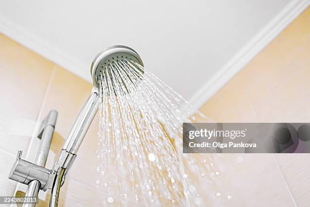 shower head spraying water in bathroom for hygiene - douche stockfoto's en -beelden