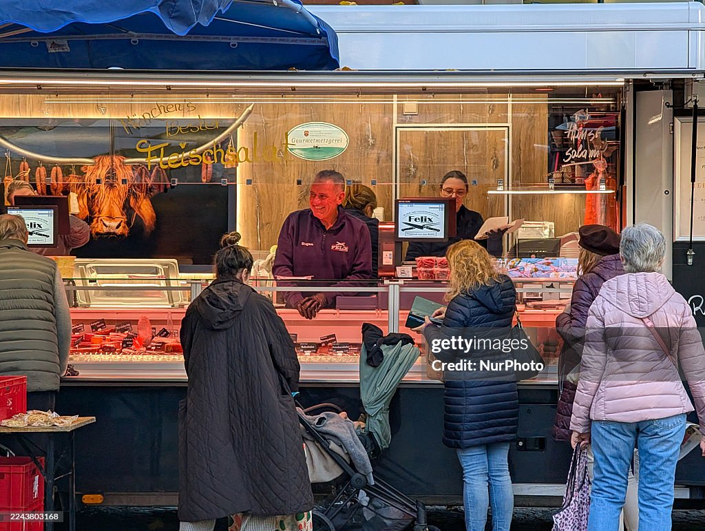 Customers Queue At Gourmet Butcher Meat Stall On Market