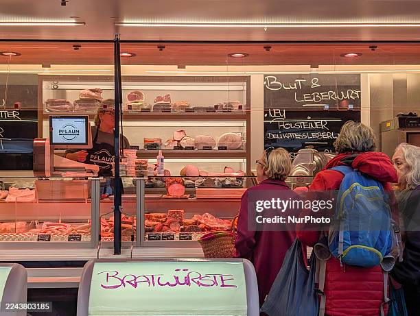 Customers queue to purchase meat and sausage products from a professional butcher stall in a market at Rotkreuzplatz in Munich, Bavaria, Germany, on...