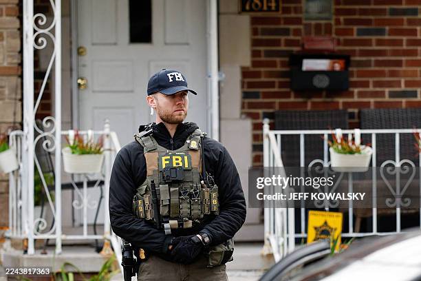 Member of the FBI Joint Terrorism Task Force stands watch in the front yard as law enforcement searches a home in Dearborn, Michigan, on October 31,...
