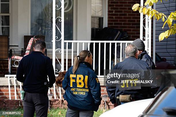 Members of the FBI Joint Terrorism Task Force stand in the front yard as they search a home in Dearborn, Michigan, on October 31, 2025. FBI Director...