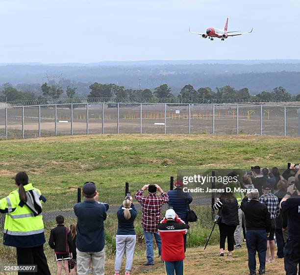 Airport workers and locals watch as a 737 jet aircraft approaches the runway for the first time at Western Sydney International Airport on October...