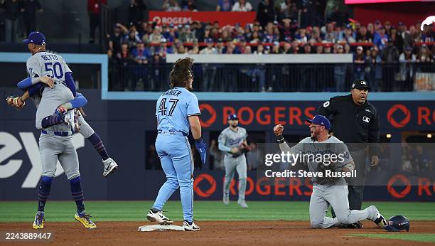 Shortstop Mookie Betts of the Los Angeles Dodgers jumps into first baseman Enrique Hernández of the Los Angeles Dodgers arms as Miguel Rojas of the...