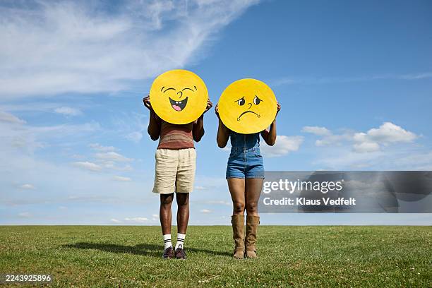 friends covering face with sad and happy smiley face - emotional series stock pictures, royalty-free photos & images