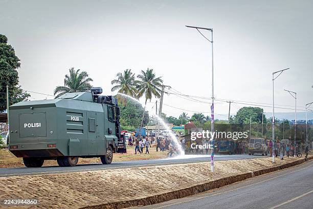 Supporters of ACT-Wazalendo party disperse as a Tanzanian Police water canon shoots water at them during a protest in Kigoma on October 30, 2025 a...