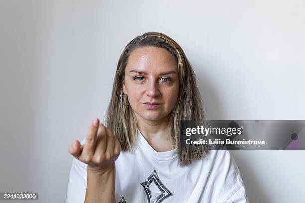 friendly woman makes an inviting gesture with extended hand in a studio portrait, conveying warmth and welcome - heranlocken stock-fotos und bilder