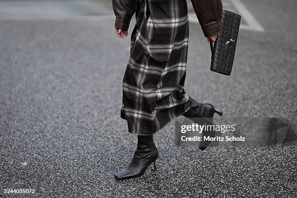 Amanda Azoitei is seen wearing a dark brown oversized leather bomber jacket with a high collar and contrast stitching by The Frankie Shop; a black...